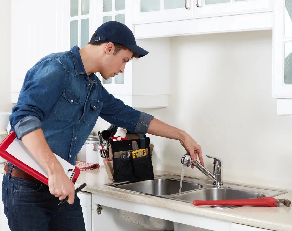 A man is working in the kitchen with tools.