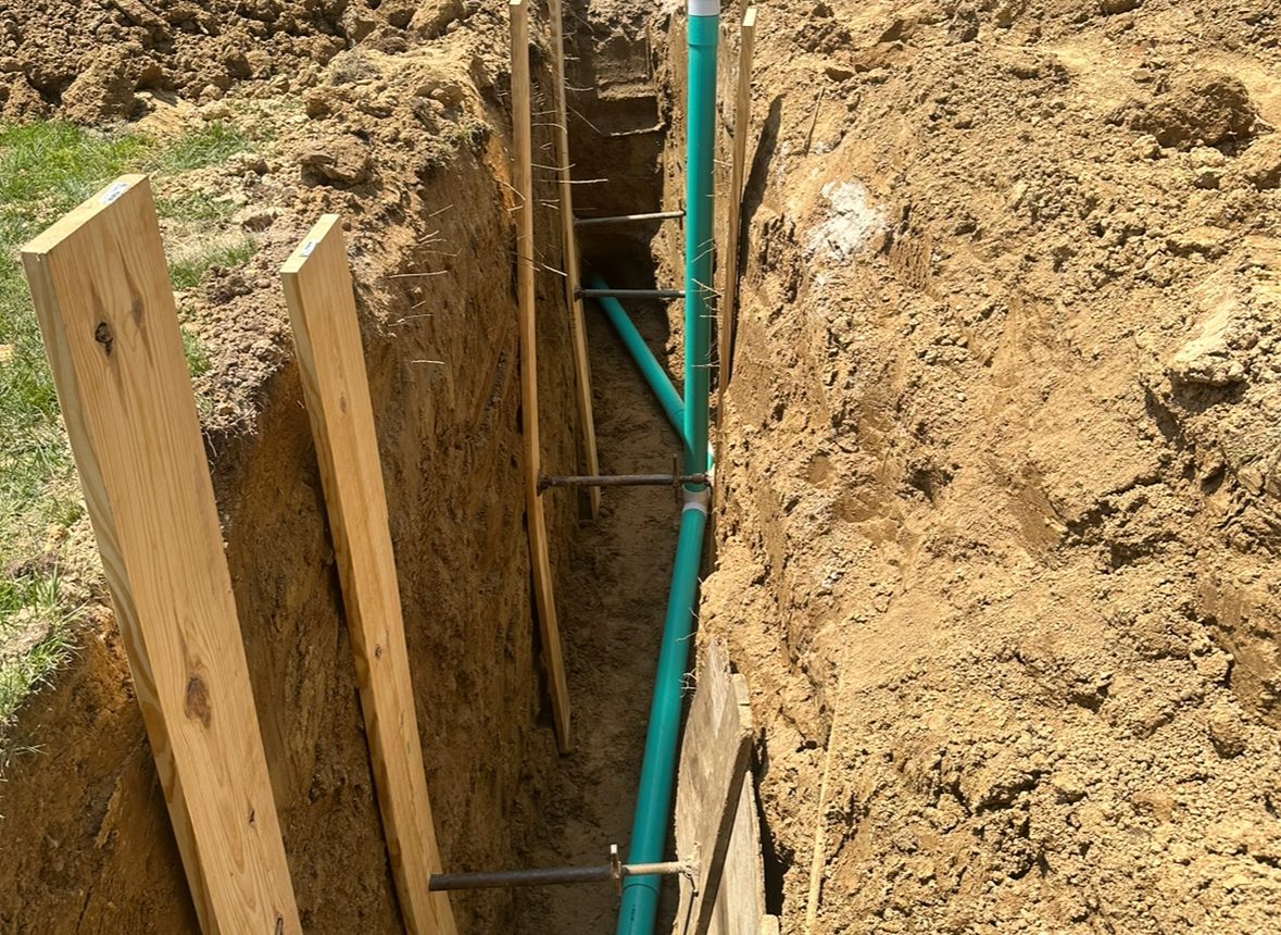 A green pipe is in the ground next to some dirt