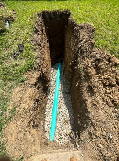 A pipe is laying in the ground near some grass.